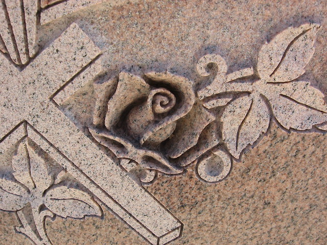 close up image of cross and rose engraving on rose granite