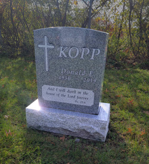 single person monument in gray granite with cross on left hand side